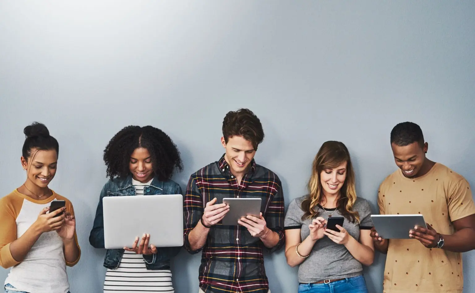 Personas con dispositivos electrónicos como tablets o móviles viendo algo en las pantallas, como el glosario de términos sobre aplicaciones y herramientas relacionados con la IA de SocraTech